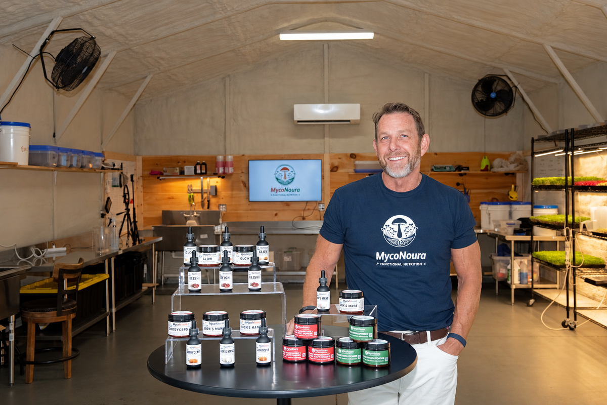 shane founder of myconoura next to product line